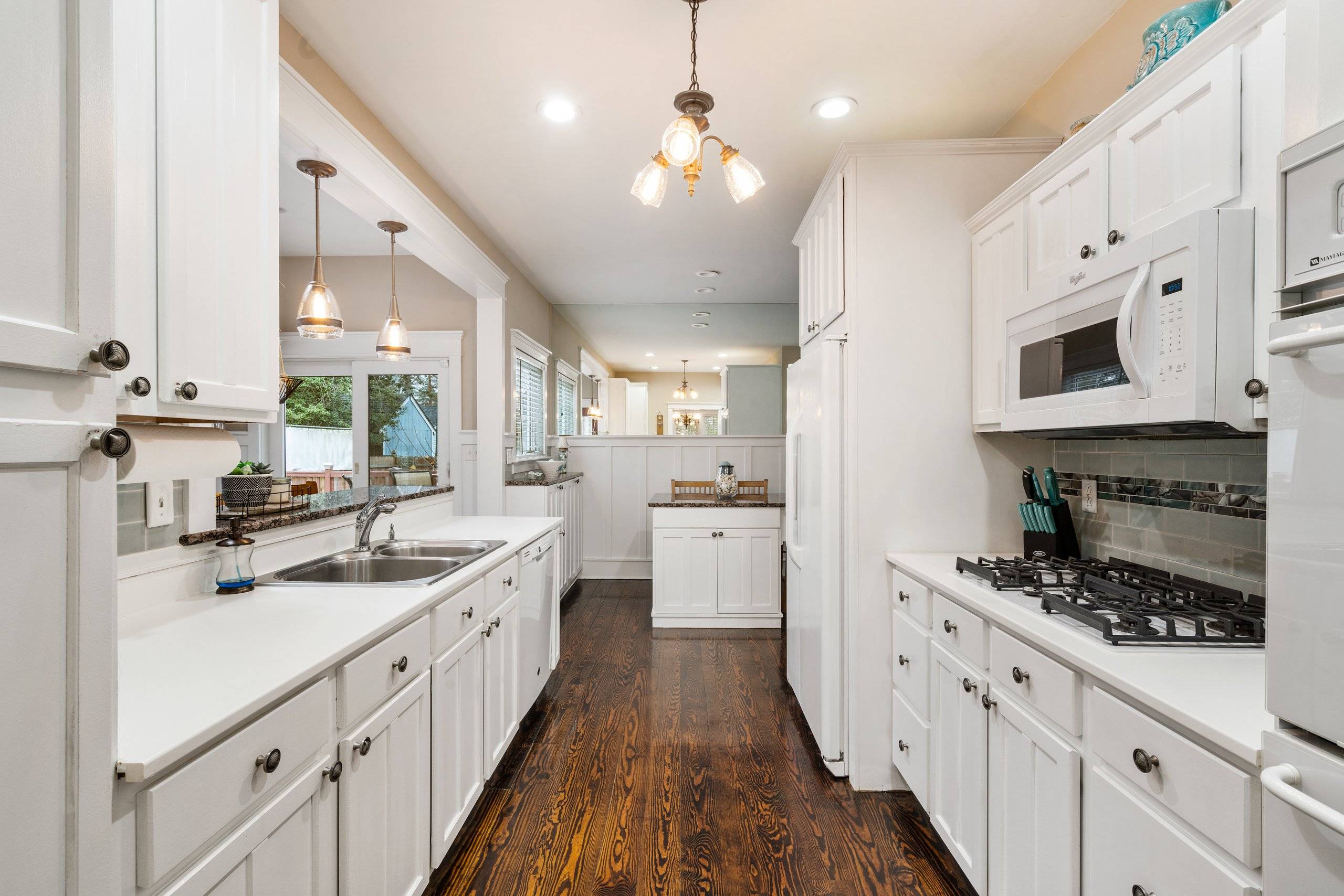 Galley kitchen with gas range and island beyond